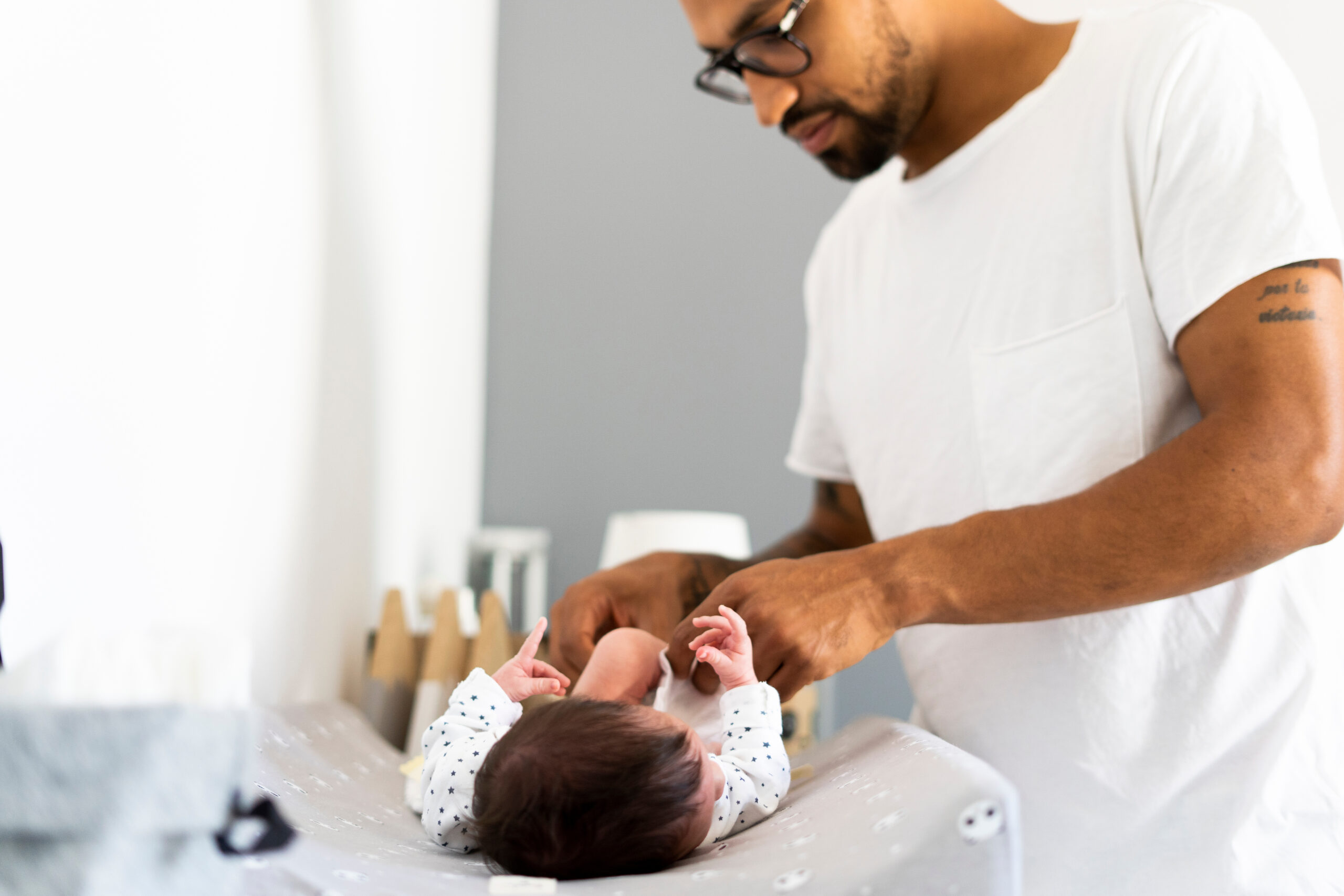 A father changing his newborn baby's diaper at a well-organized diapering station, highlighting essential care steps for new parents.