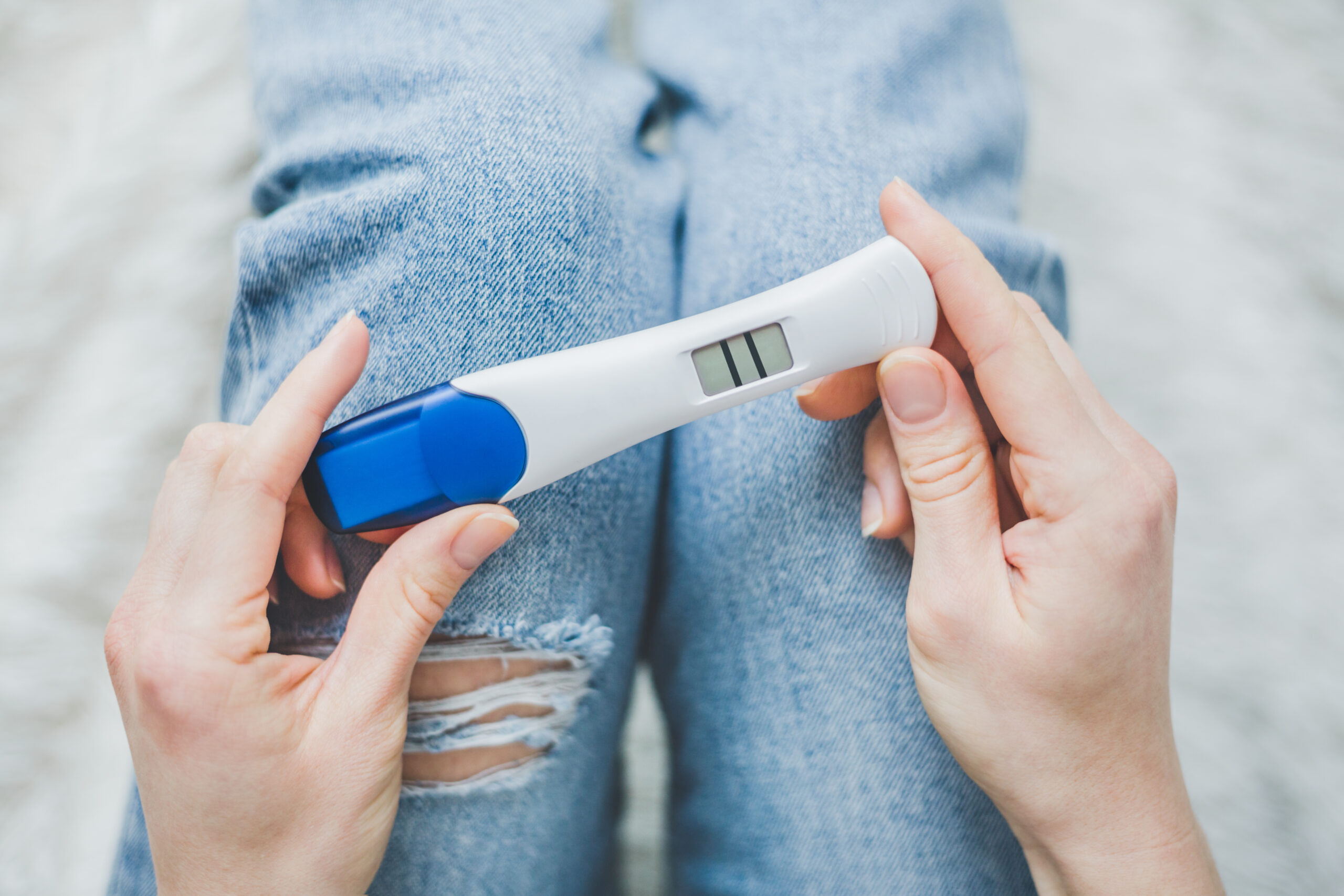 A woman smiling as she looks at a positive pregnancy test in her hands, symbolizing the start of her pregnancy journey